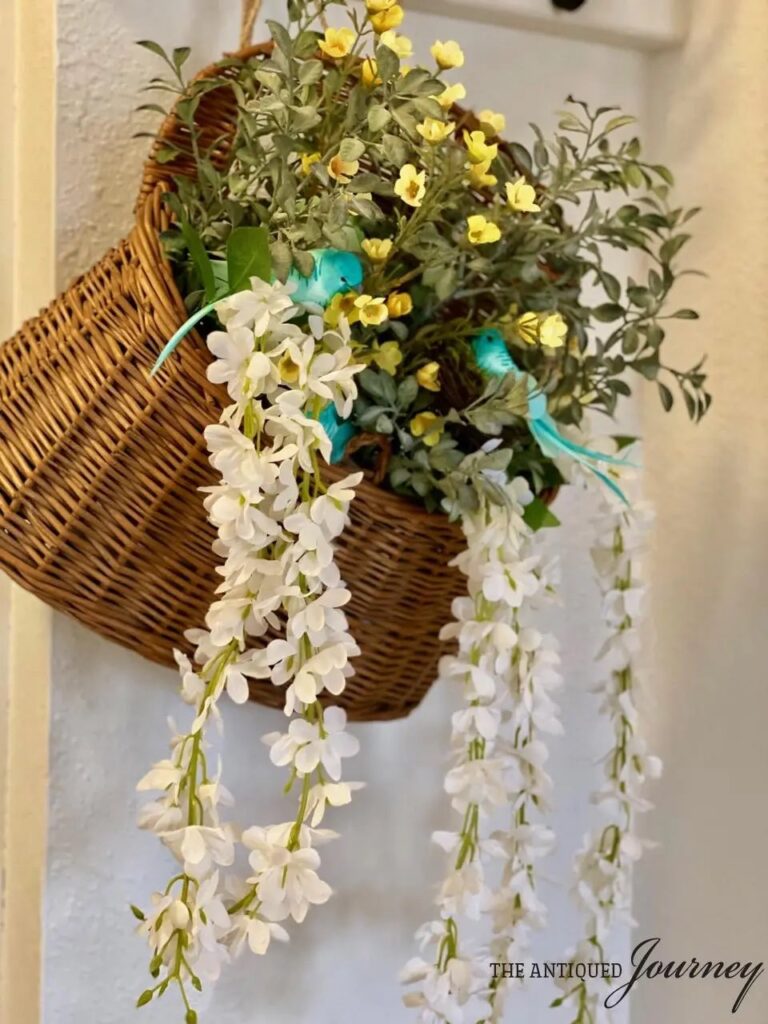 closeup of a vintage basket overflowing with Spring blooms and a small nest with birds