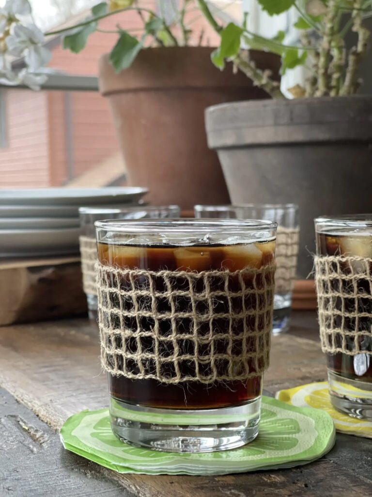 closeup of two glasses. filled with icee and a cola beverage and the glasses are. wrapped with jute "lace"