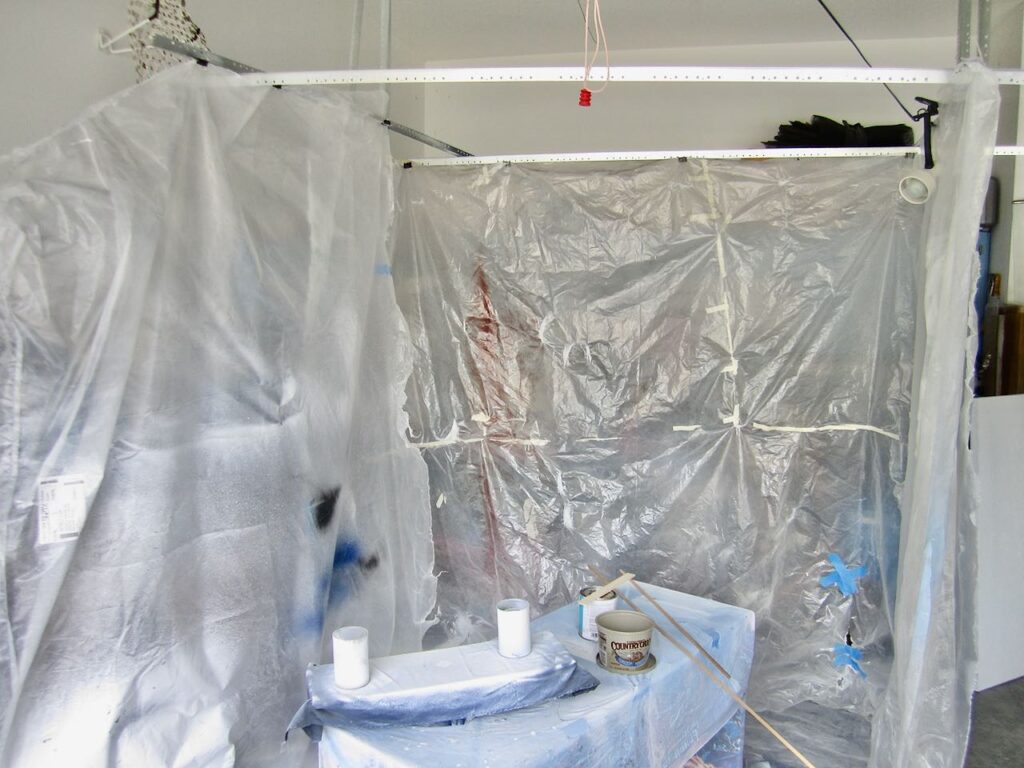 View inside the spray paint tent with a small craft porject on a plastic covered table