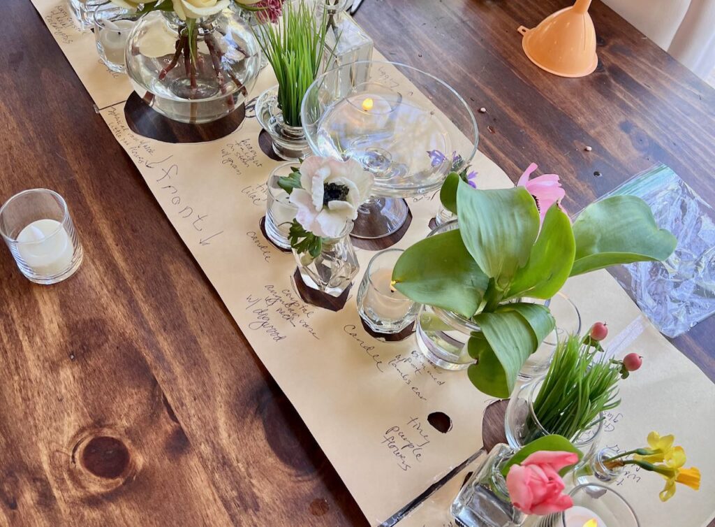 Closeup of. the bridal table with the centerpiece map being filled with the matching vases and flowers and candles