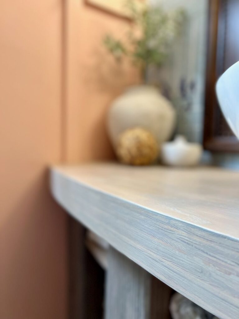 super close up image of the top of the vanity focusing on the thick apron front. Decor pieces are out of focus in the background