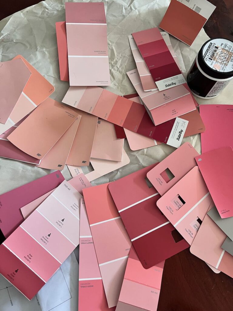 a large pile of various coral swatch cards spread out on a wood table top