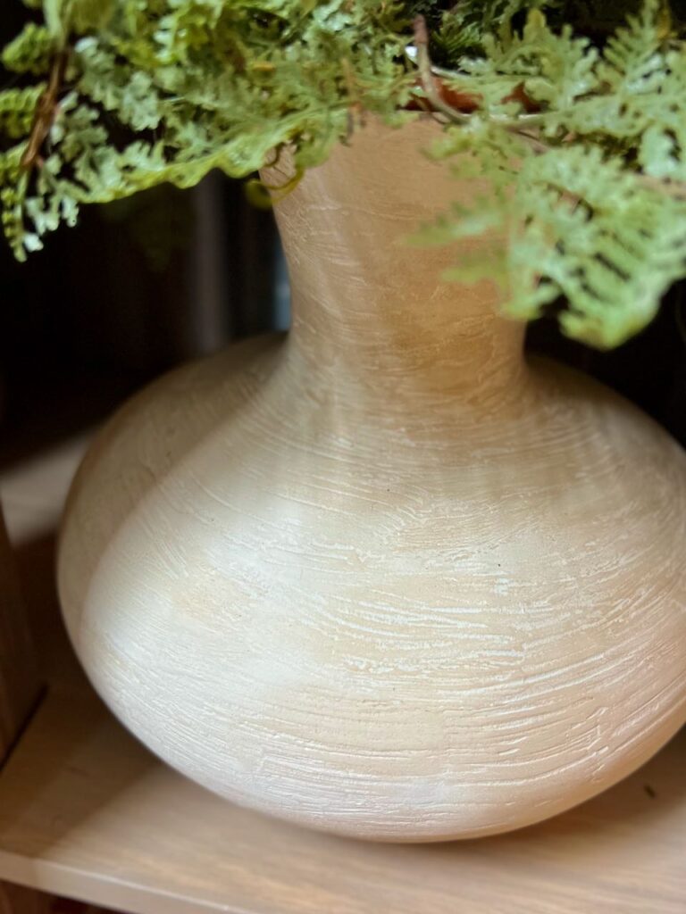 super close up view of a made over vase with a fern on the bottom shelf of the vanity