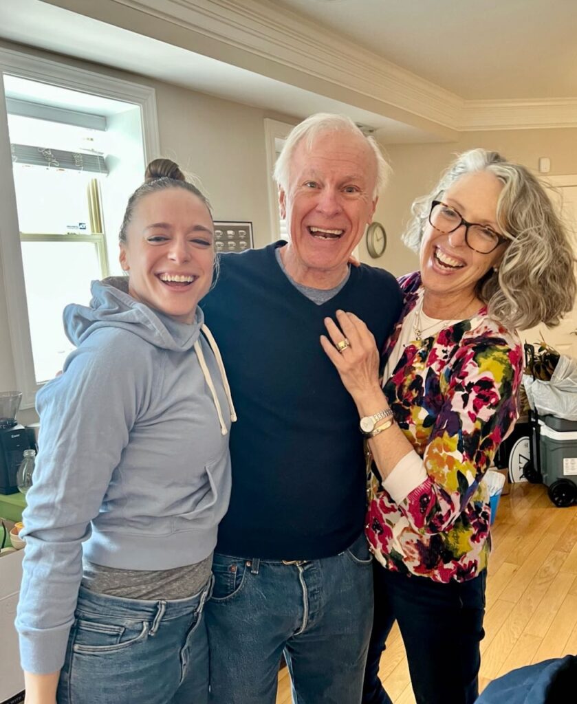 Two women on each side of a gentleman -- all laughing