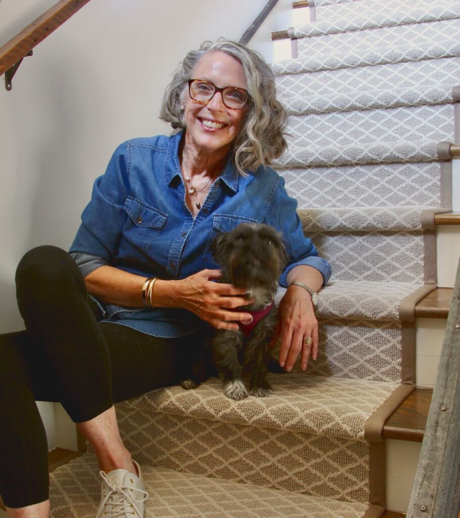 a Woman with her small dog sitting beside her on the newly painted steps with stair runner installed