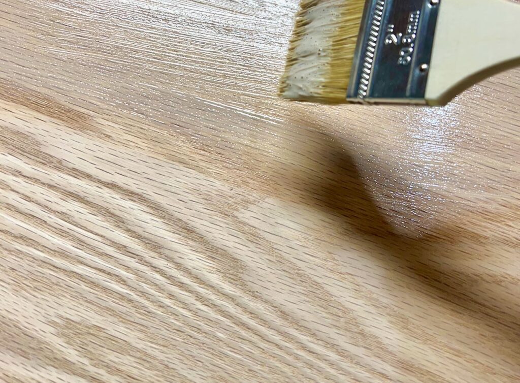 a closeup of a bit of a paint brush. showing in the middle of a swipe of glaze on a shelf