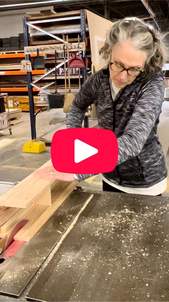 woman feeding a three-sided beam through a table saw with video play button