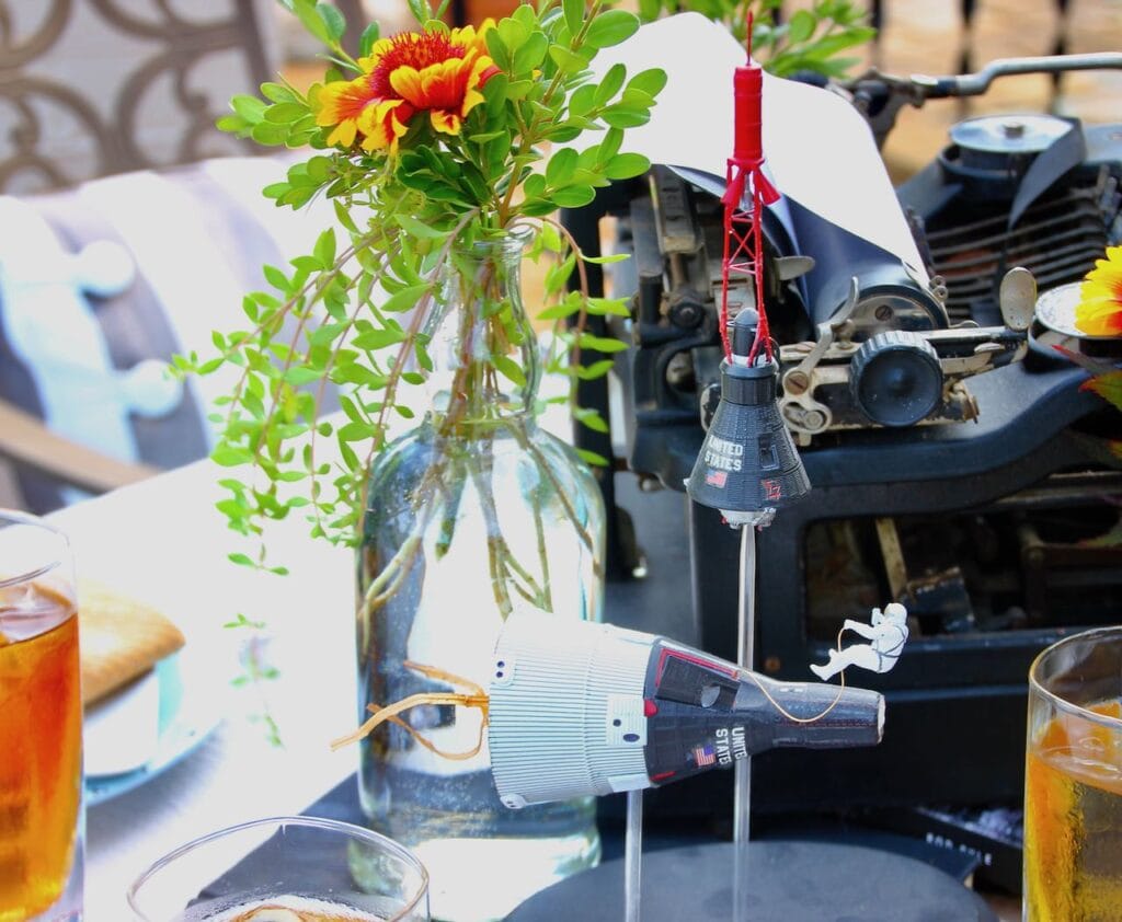 Closeup of the Fathers Day centerpiece featuring the model with the Apollo space module and an astronaut in space walk next to the vintage typewriter