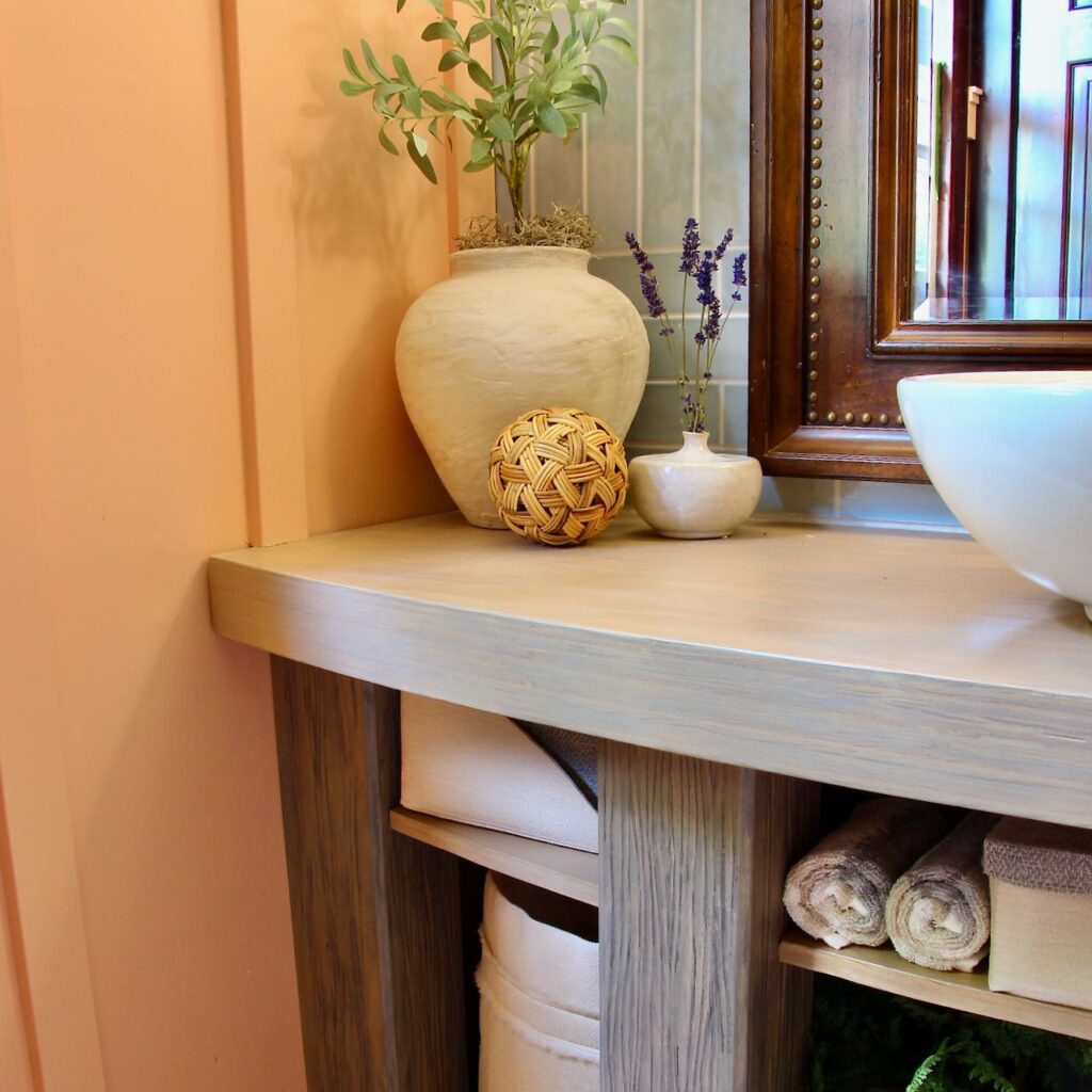 Closeup of the corner of the wooden bathroom countertop with the legs and decor pieces in place on top