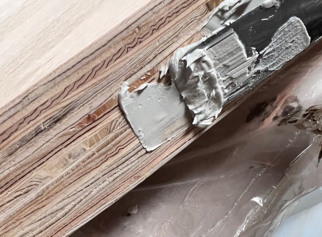 closeup of putty knife spreading joint compound on the front curved edge of the countertop