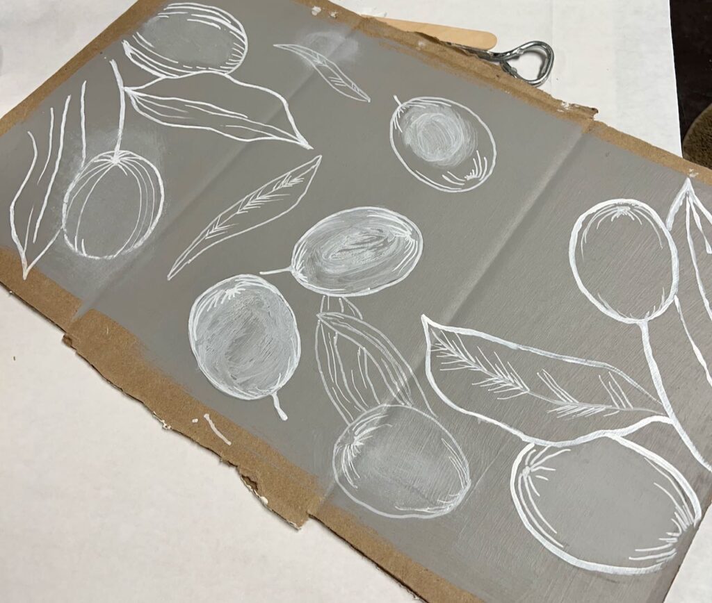 a piece of cardboard is painted the wall color and there are quite a few samples of olives and leaves painted with different styles of shading and lines