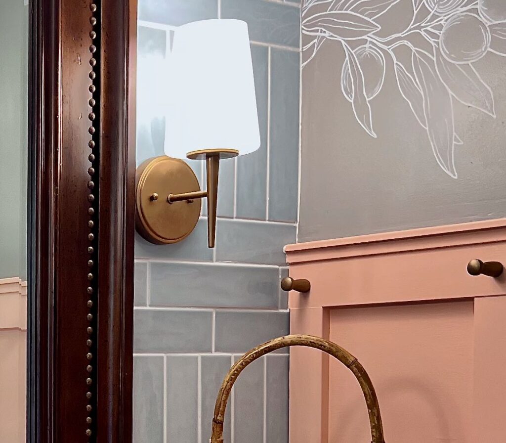 closeup of three gold decor accents: gold nailheads on the mirror with the new gold finish of the light fixtures with the gold pegs on the board and batten wall treatment