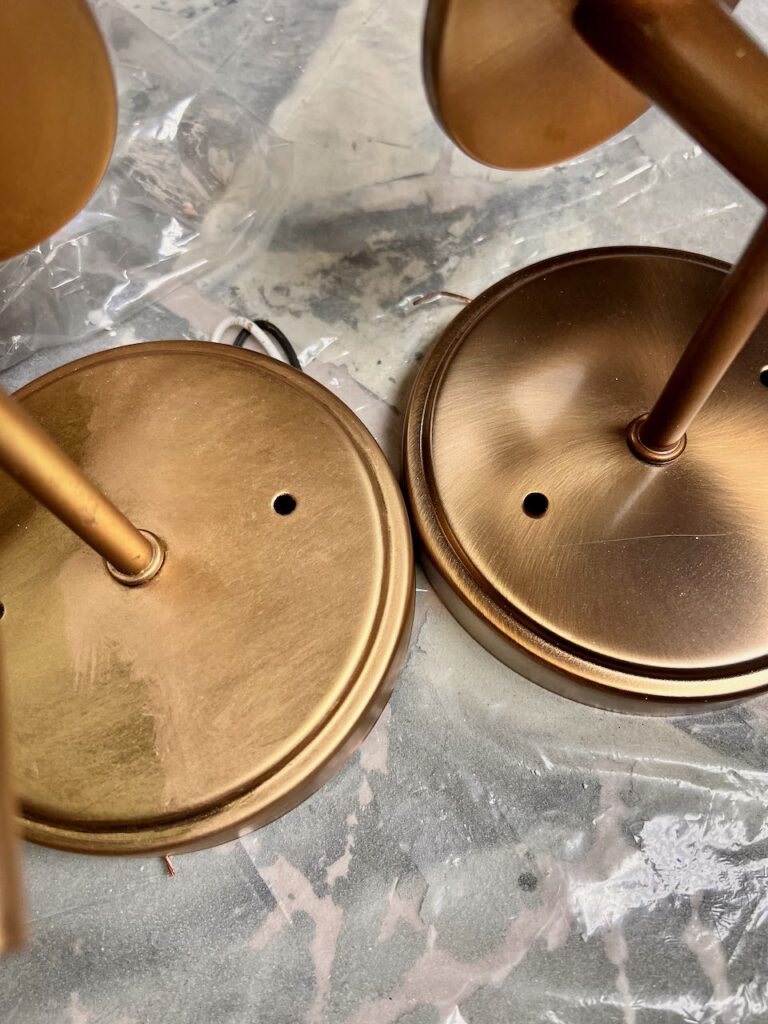 the base of identical light fixtures next to each other showing the difference in the gold tones