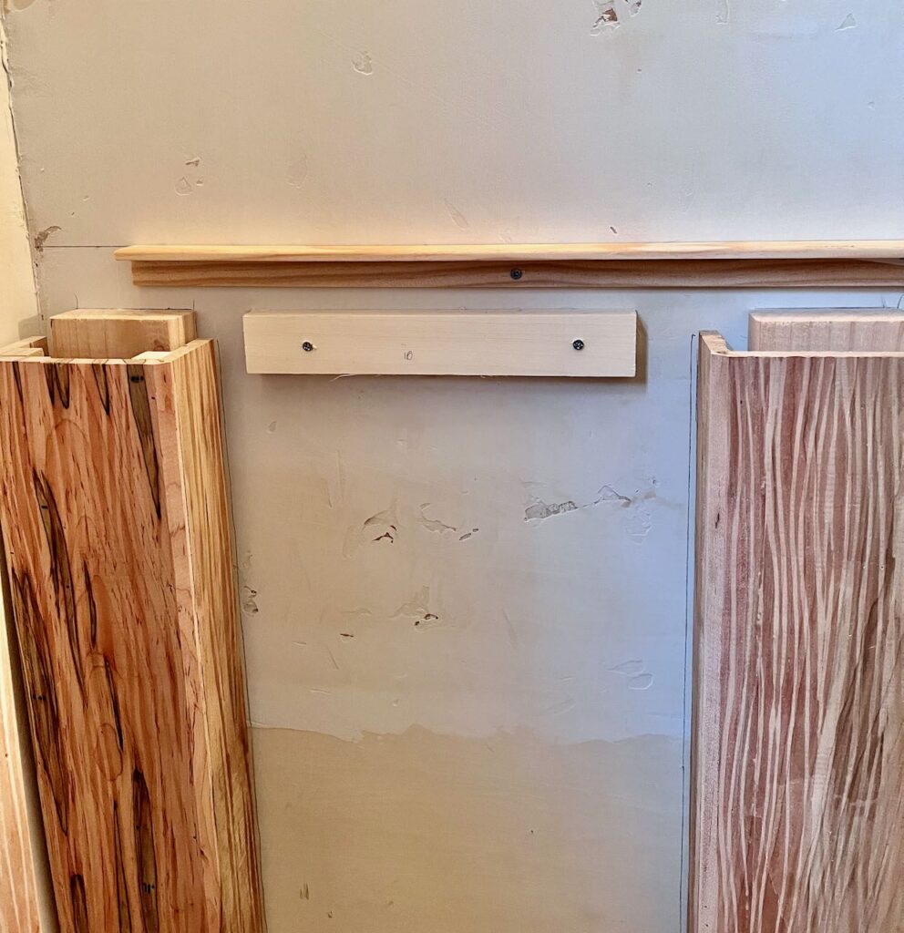 view of two legs standing against the wall with lines drawn close to the legs and at countertop height. A piece of trim is installed horizontally at the countertop line