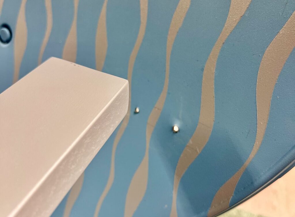 Super closeup of the holes drilled through the back of the repurpose satellite dish where screws will come through and attach the wood armrests armrest attached to the swing back showing the slight angles involved