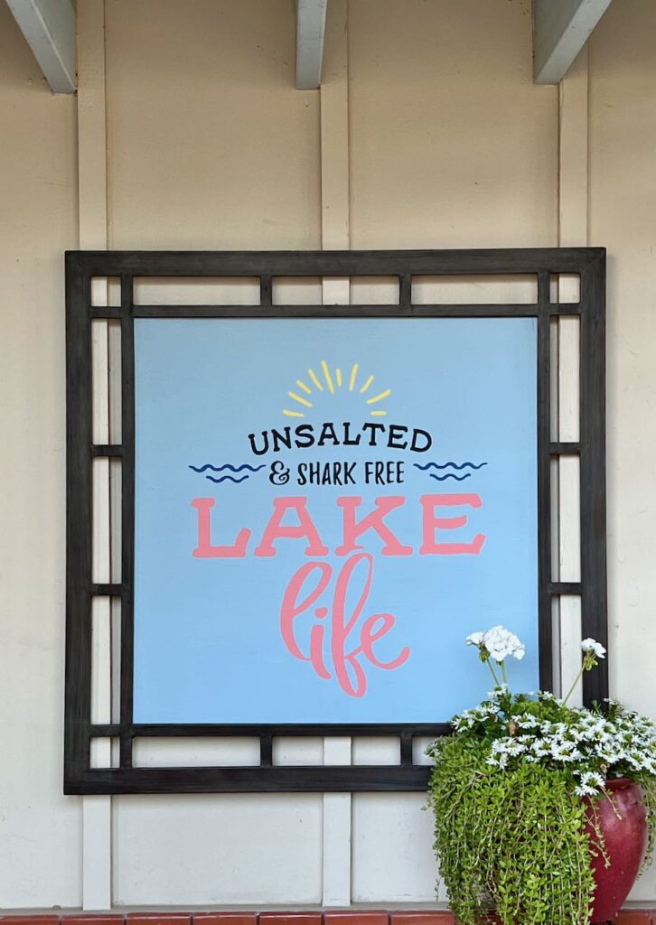 The final patio sign framed and hanging outside with a potted plant in front of one corner