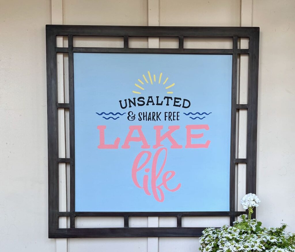 finished fun patio sign about lake life framed and hanging outside with a potted plant in front