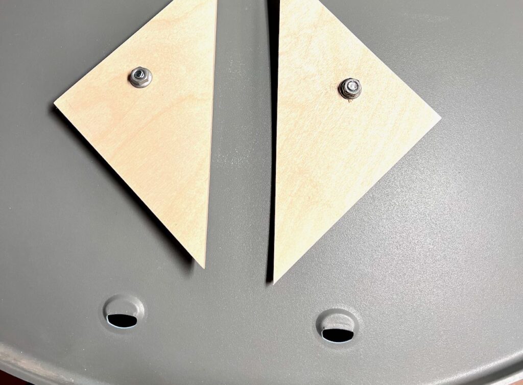 closeup of wood triangles bolted to bottom of swing to keep satellite arm from moving side to side