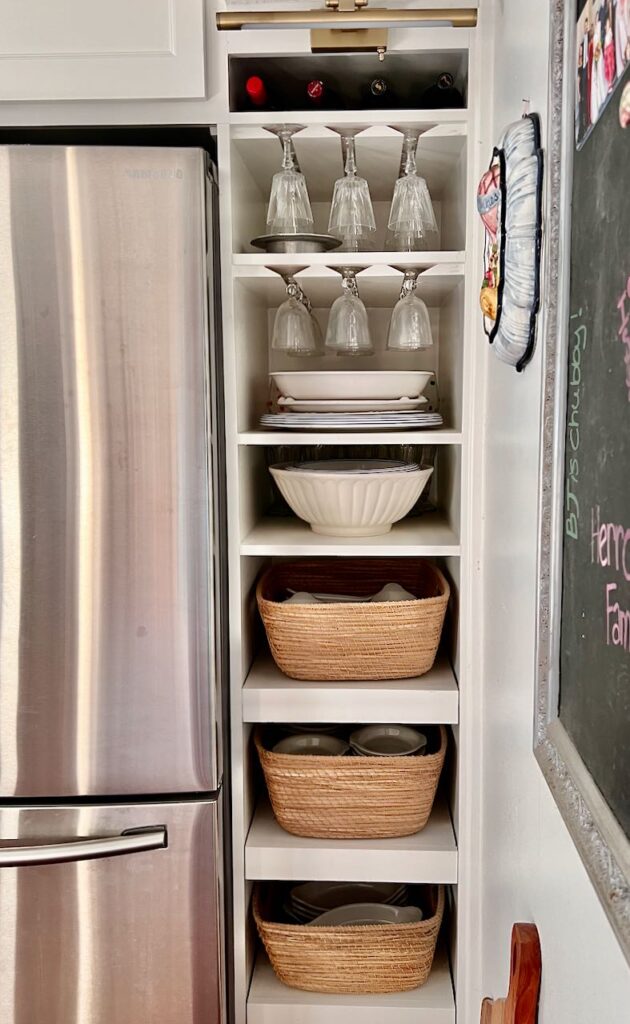 Tall, narrow "entertaining zone" next to a refrigerator with platters, wine glasses above three baskets on pull out shelves