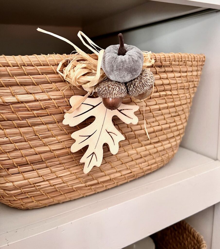 Bundle of wood leaf with a bronzed acorn, a mini velvet pumpkin and some raffia wired together and onto a basket 