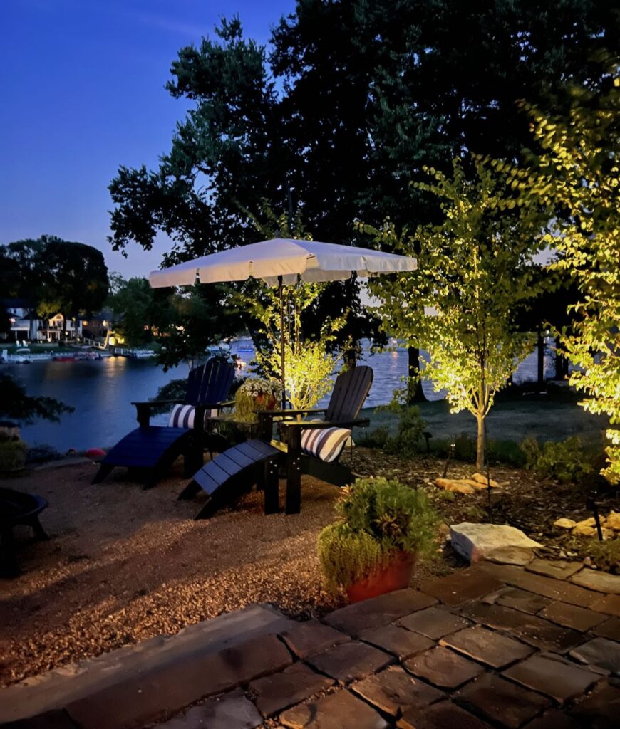 three trees around a gravel patio are shown uplit against a night backdrop