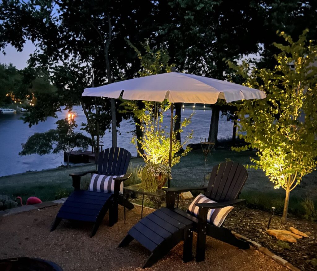 two trees against a night backdrop are shown uplight by a solar light