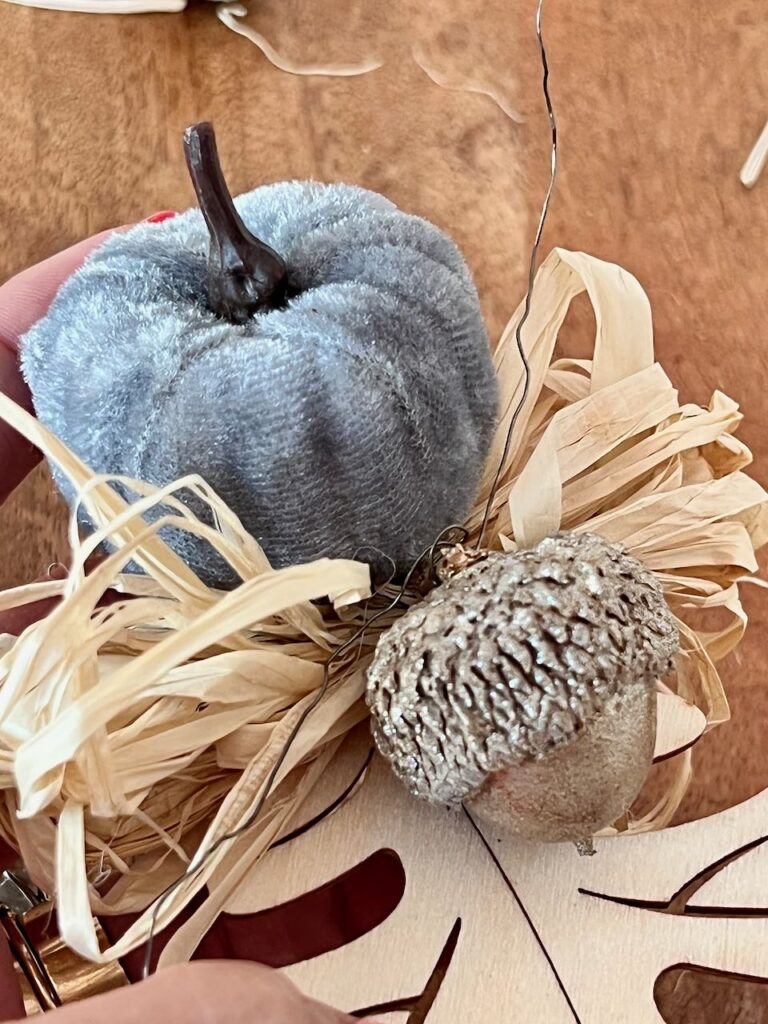 Closeup of the wood leaf with the raffia, pumpkin and acorn all wired together