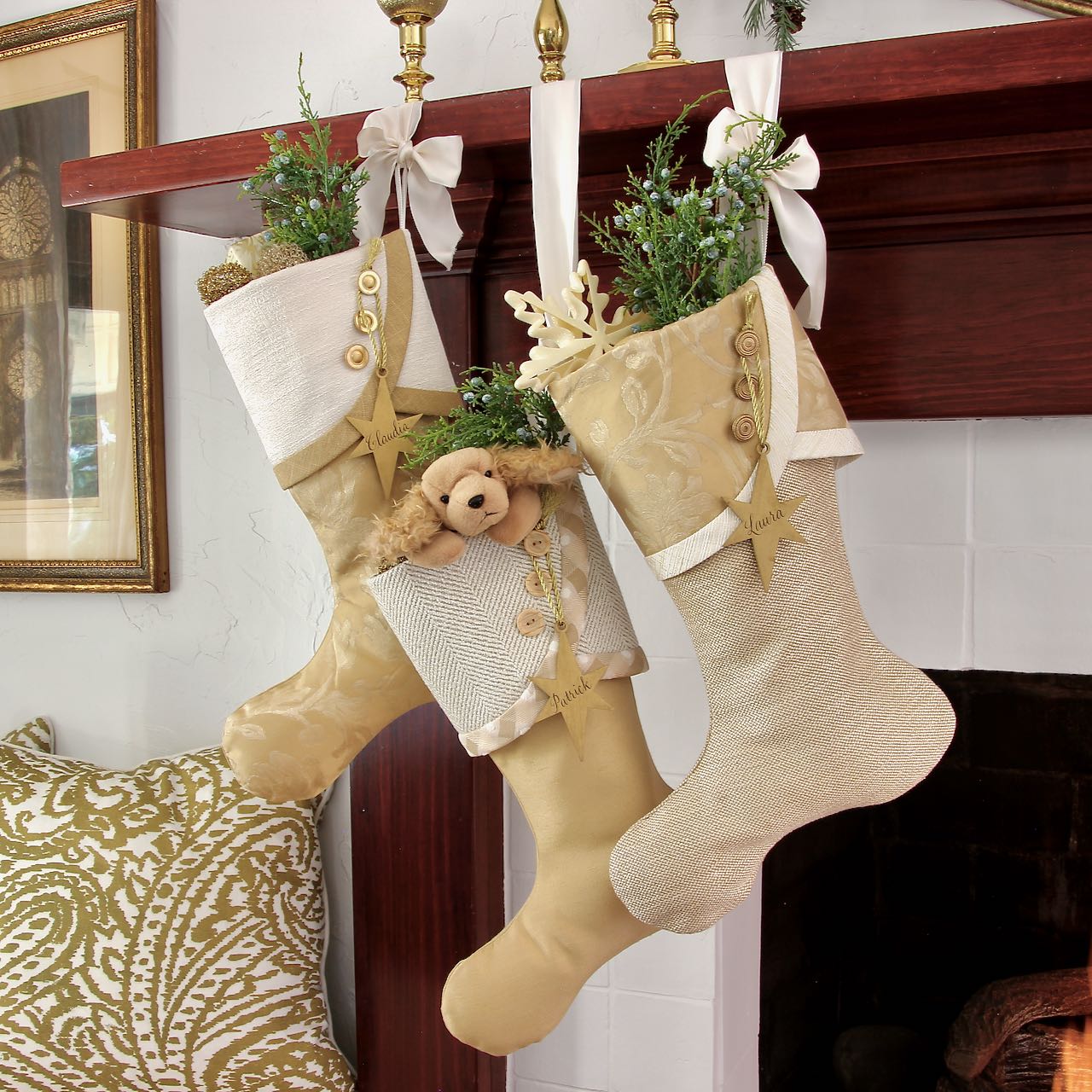 3 gold Christmas stockings with gold star name tags hanging from wood mantel