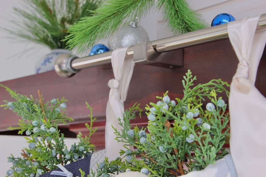 Closeup of silver hook attached to front of mantel cover holding a stocking rod with two stockings