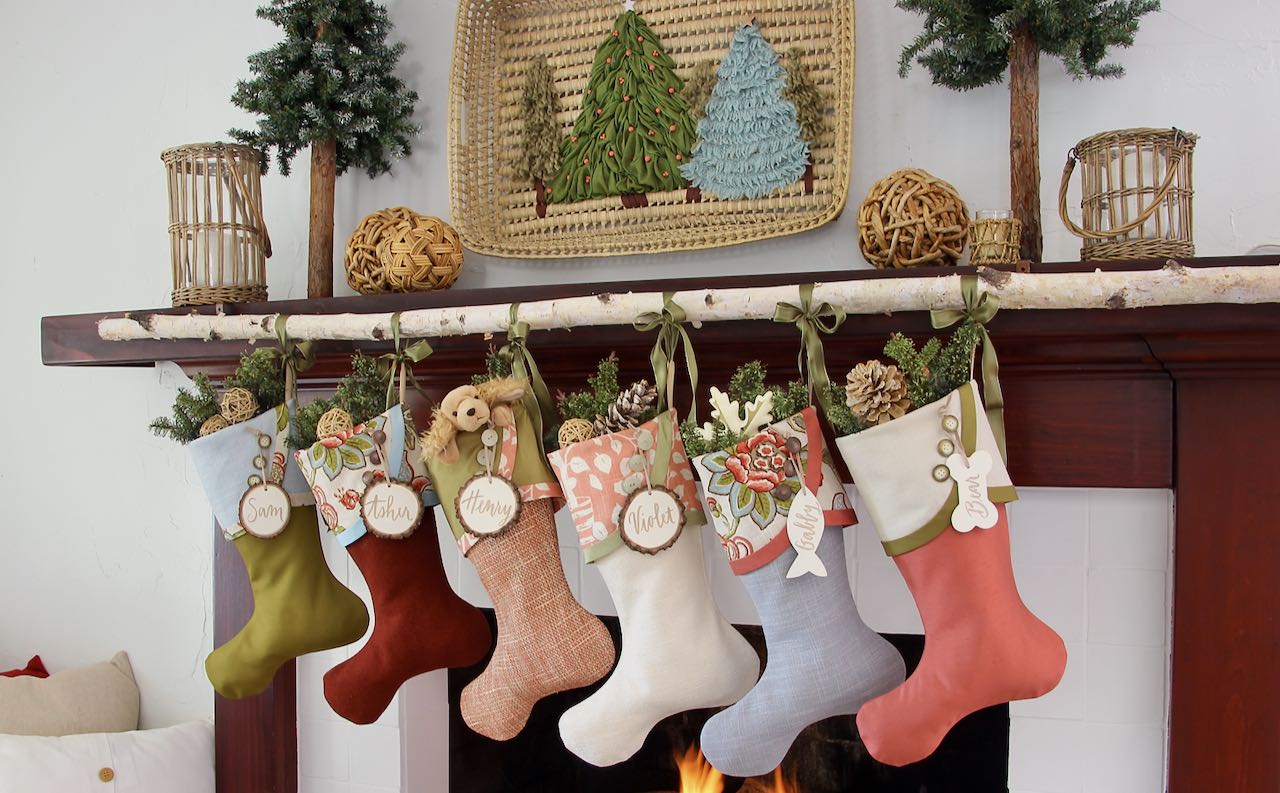 wide view of 6 cottage Christmas stockings withhh white tree slice name tags