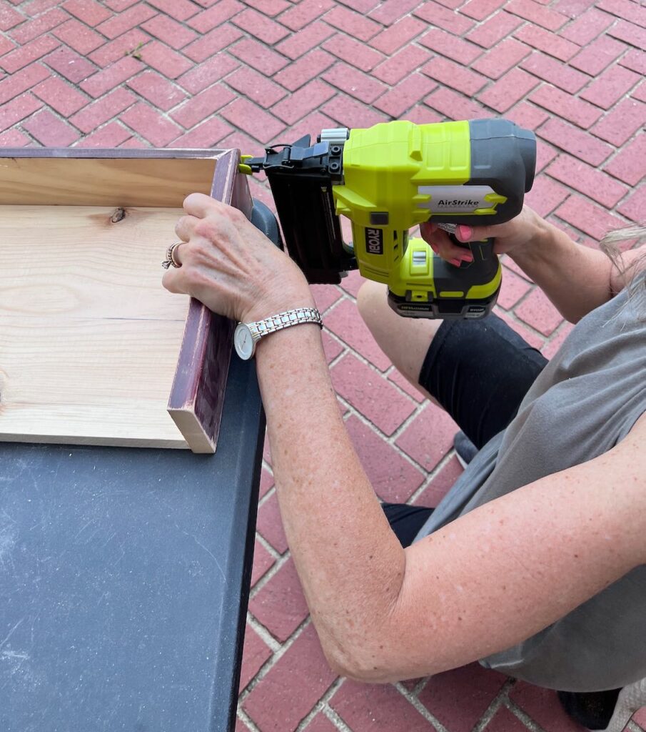 Woman's hands holding a brad nailer to a mitered corner