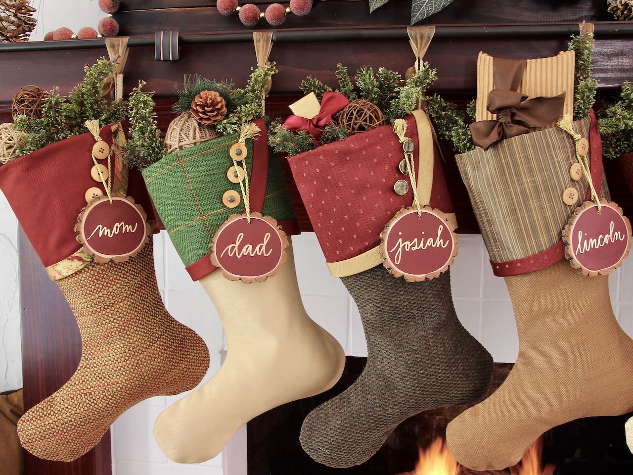 4 unique Christmas stockings hanging from dark wood mantel