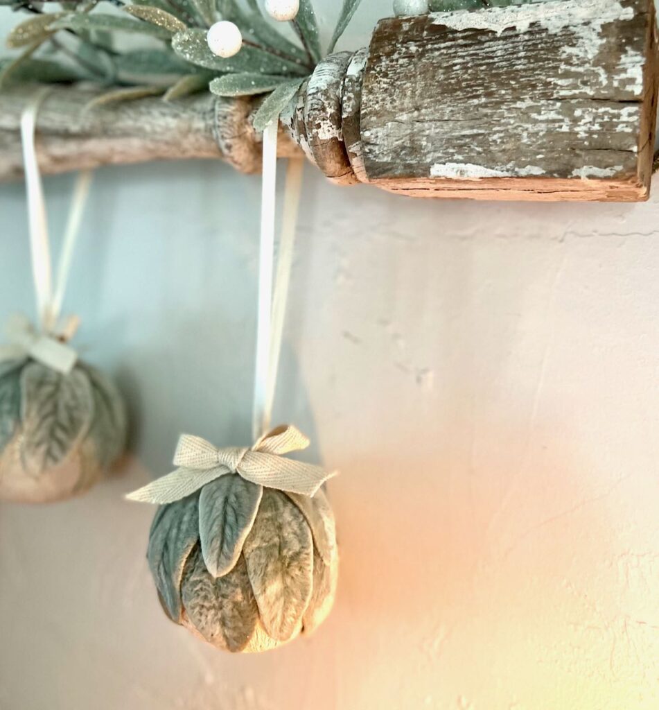 Two ornaments hanging from a vintage spindle with candlelight glowing on them