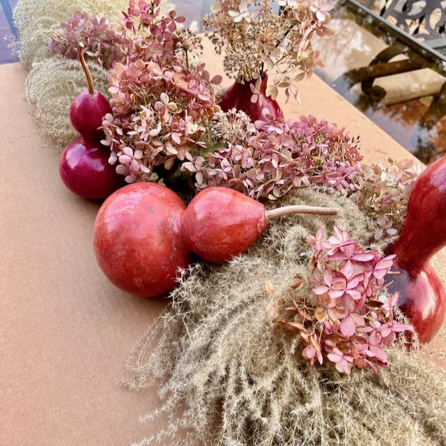 Hydrangea blooms are added in a wavy line encompassing the gourds