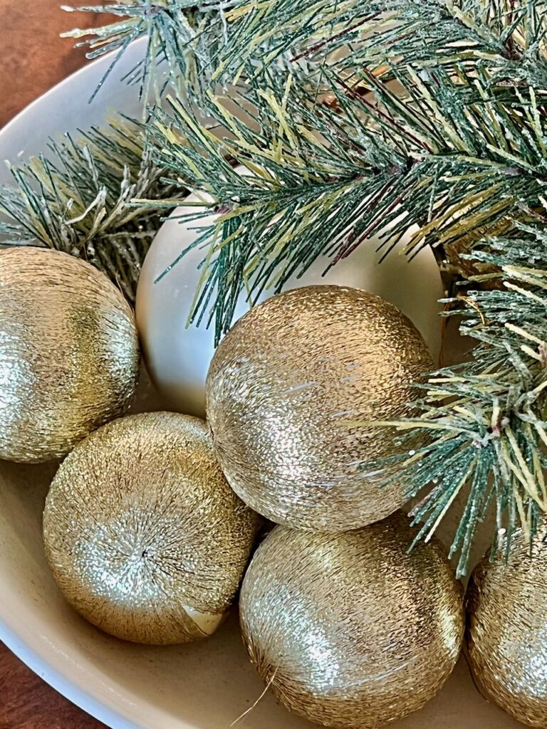 closeup of old Christmas ornaments with greenery in a bowl