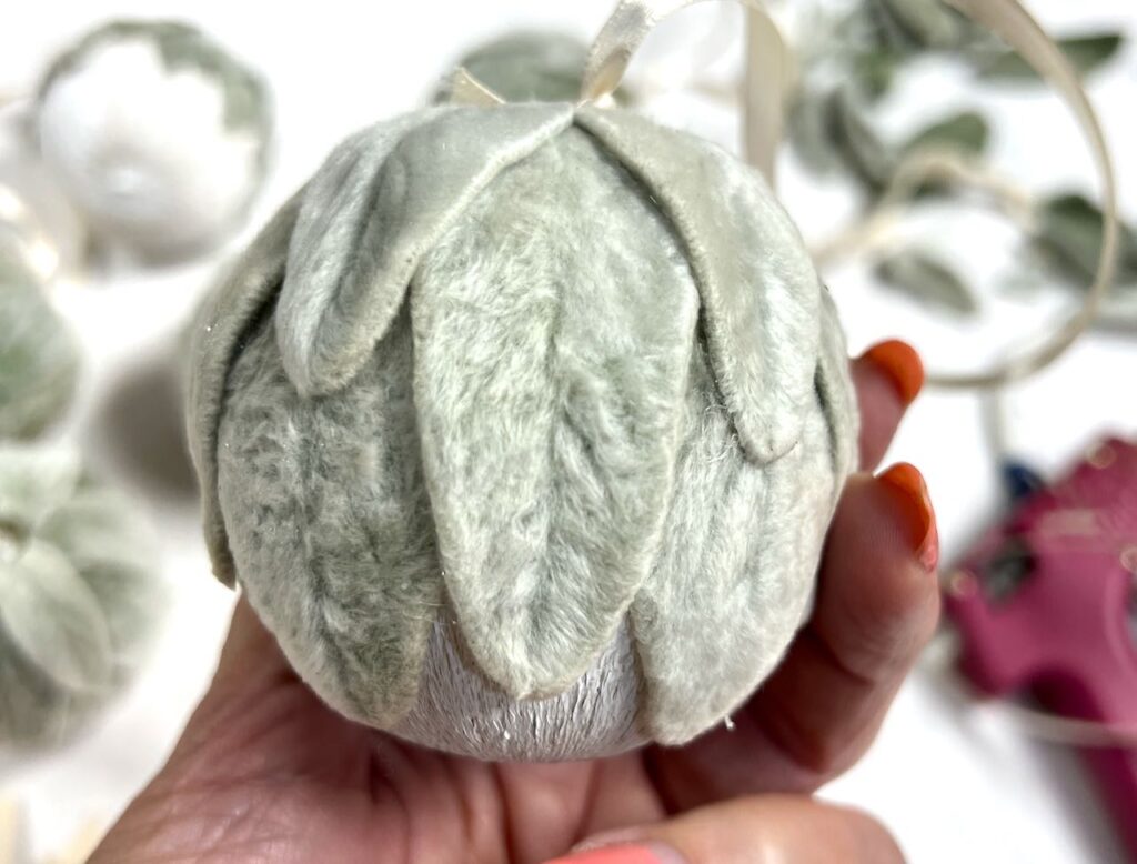 closeup of woman's hand holding a lambs ear covered Christmas Ornament