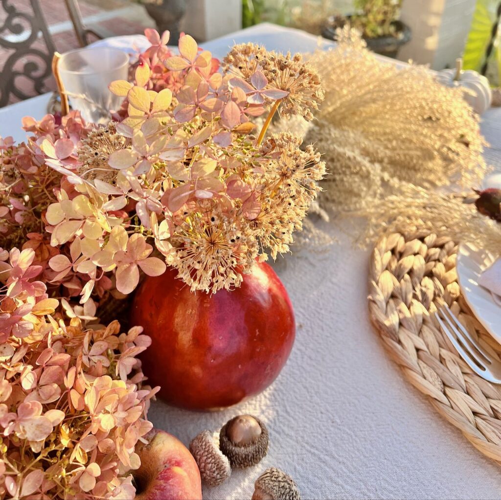 closeup of a gourd vase holding dried hydrangeas and dried alum blooms
