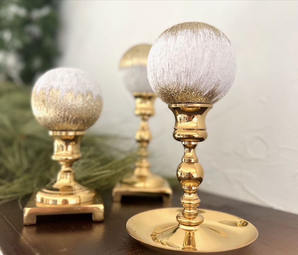 Three finished ornaments displayed on brass candlesticks