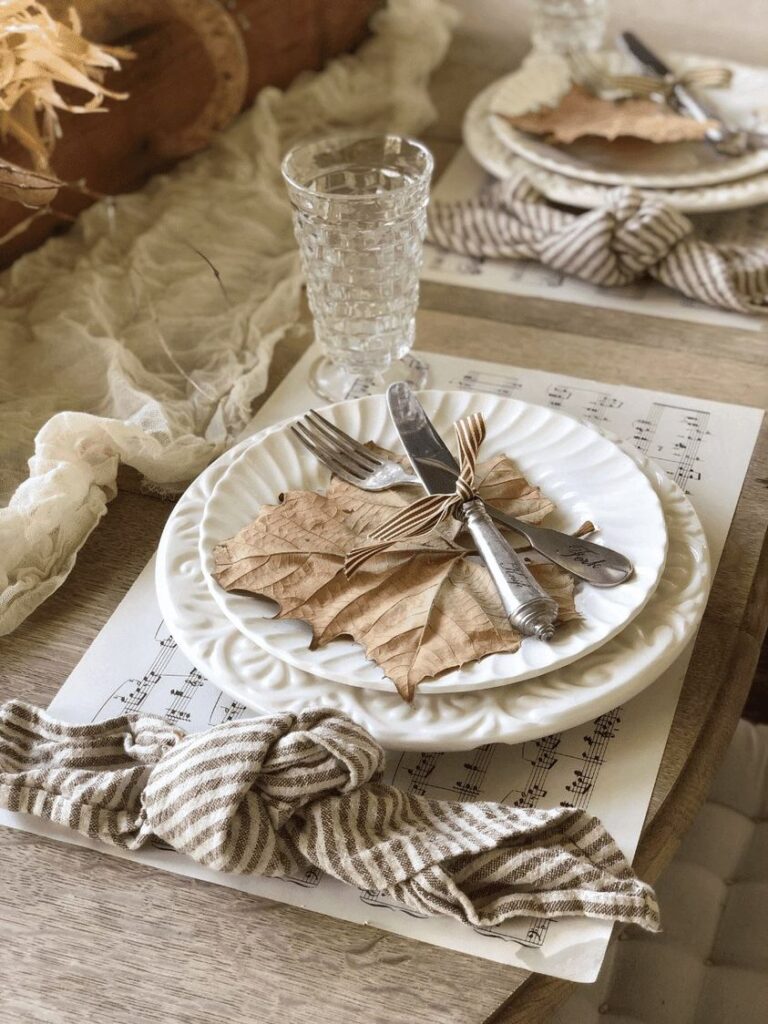 Placesetting with dried leaf and crossed knife and fork on sitting on a placemat of sheet music