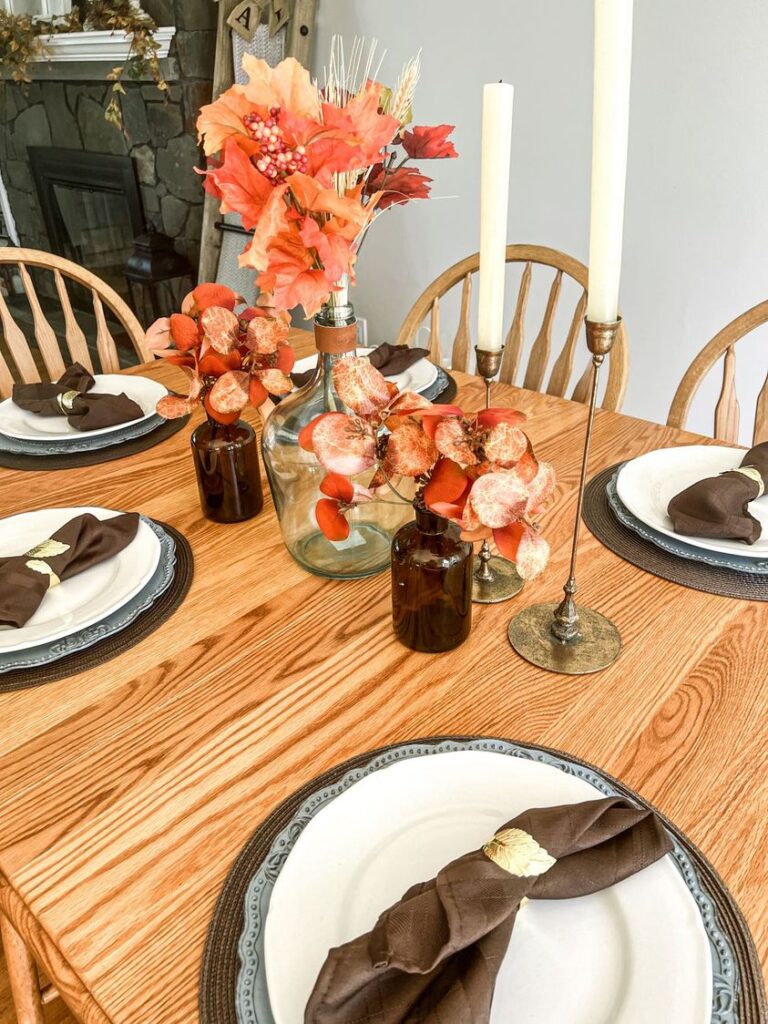 Informal Fall Table set with faux branches in amber and teal glass bottles and 