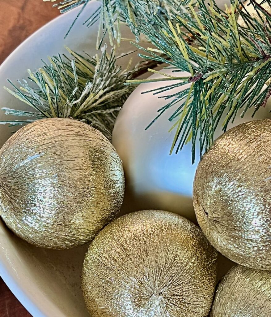 old Christmas ornaments in a bowl with a bit of greenery