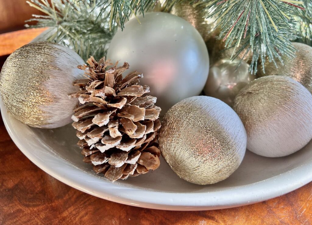 Revived Old Christmas Ornaments with greenery and a bleached glittered pinecone in a bowl