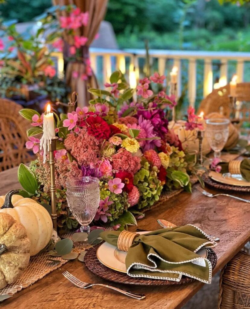 Centerpiece overflowing with garden fresh flowers flanked on each side with pumpkins and gourds