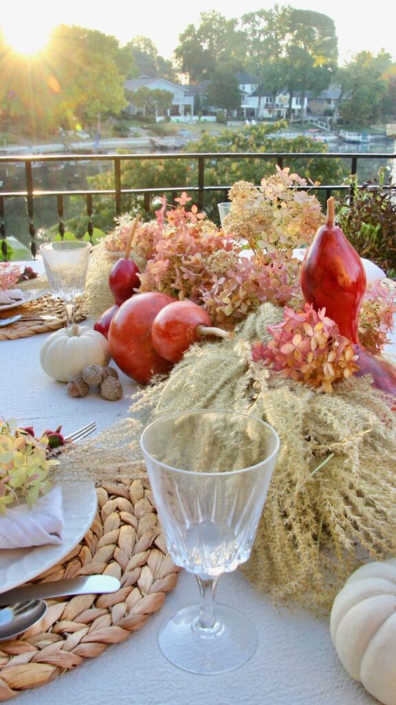 Sunrise breaking on the centerpiece of a Fall table set outdoors overlooking a lake