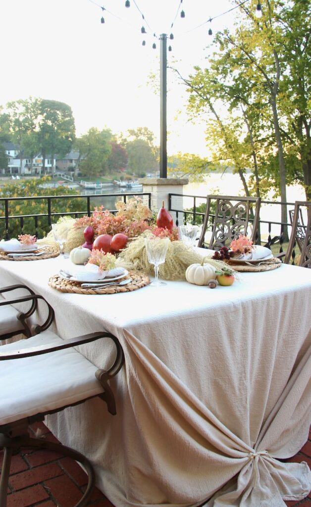 vertical image of a Fall tablescape at sunrise wit a lake in the background