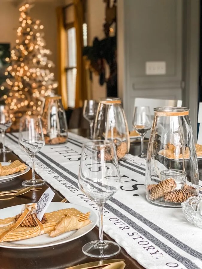 A Thanksgiving dinner table set with a runner and pinecones