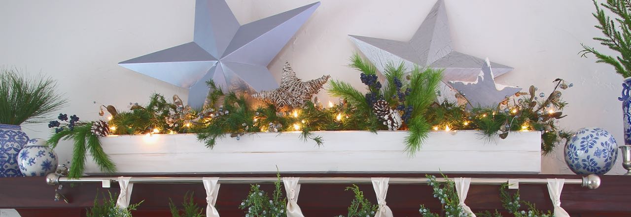 Wide title picture of four stars and greenery in a long narrow wood box on a mantel