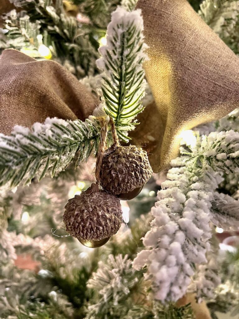 closeup of a nutcracker and ceramic house on a flocked Christmas tree