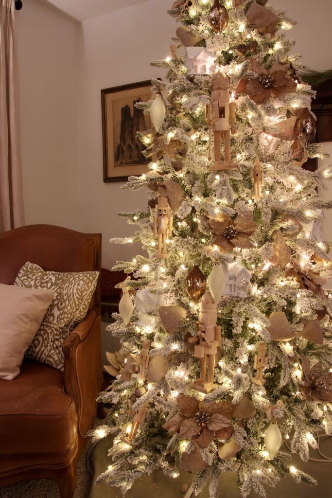 a full length view of a flocked Christmas tree all decorated at night in a living room