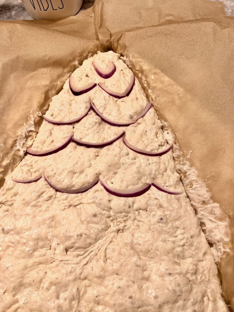 the first bits of decorations are added to the tree dough -- thin slices of red onion forming a garland